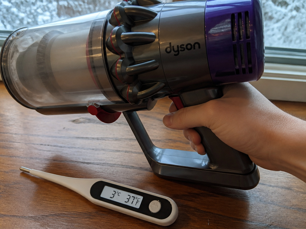 Dyson vacuum on floor with low temperature reading, trigger pressed but not running.